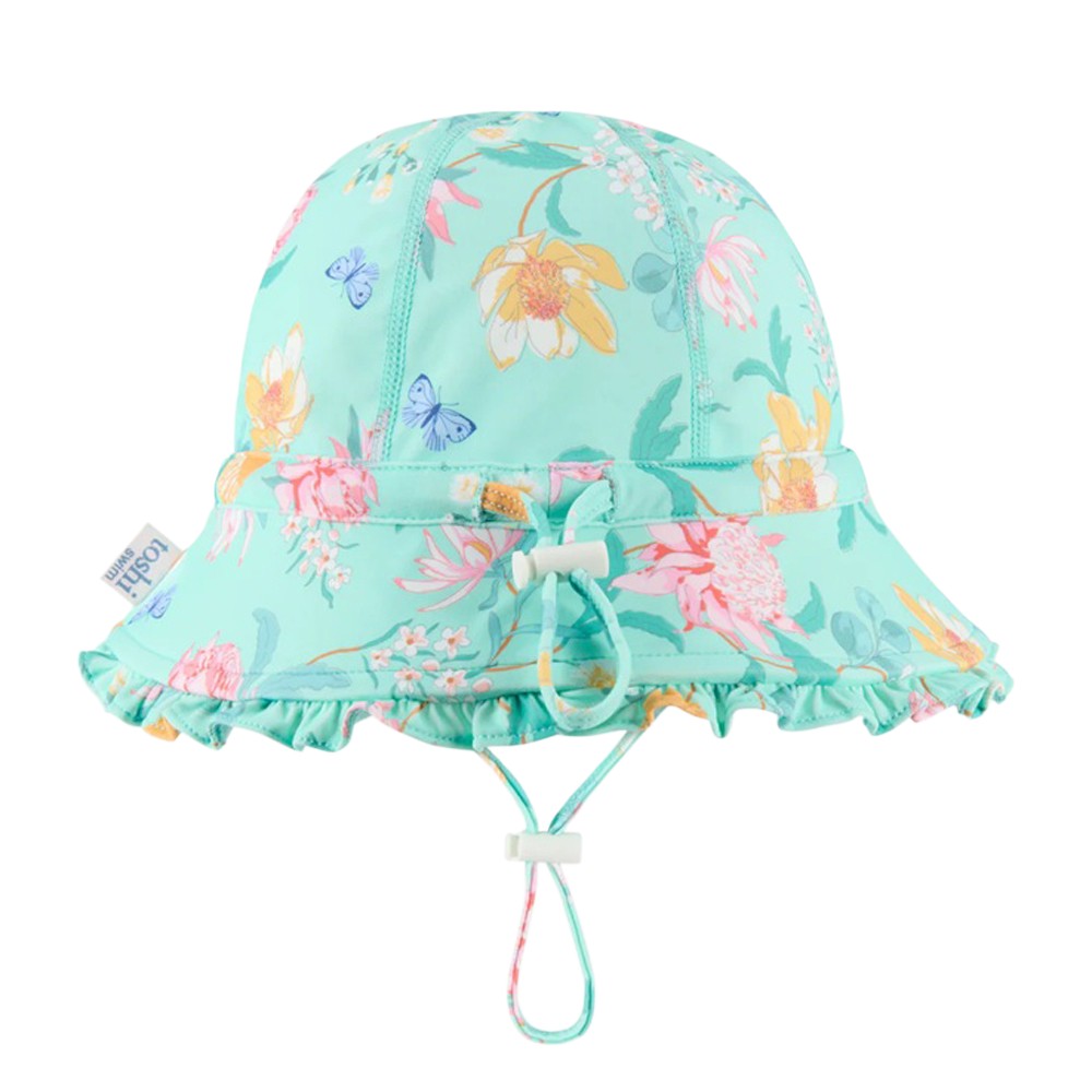 The Toshi Swim Bell Hat Ripple Waratah Mint is a light turquoise baby sunhat with a floral and butterfly print, ruffled brim, adjustable chin strap, UPF50+ protection, and a small cloth side tag.