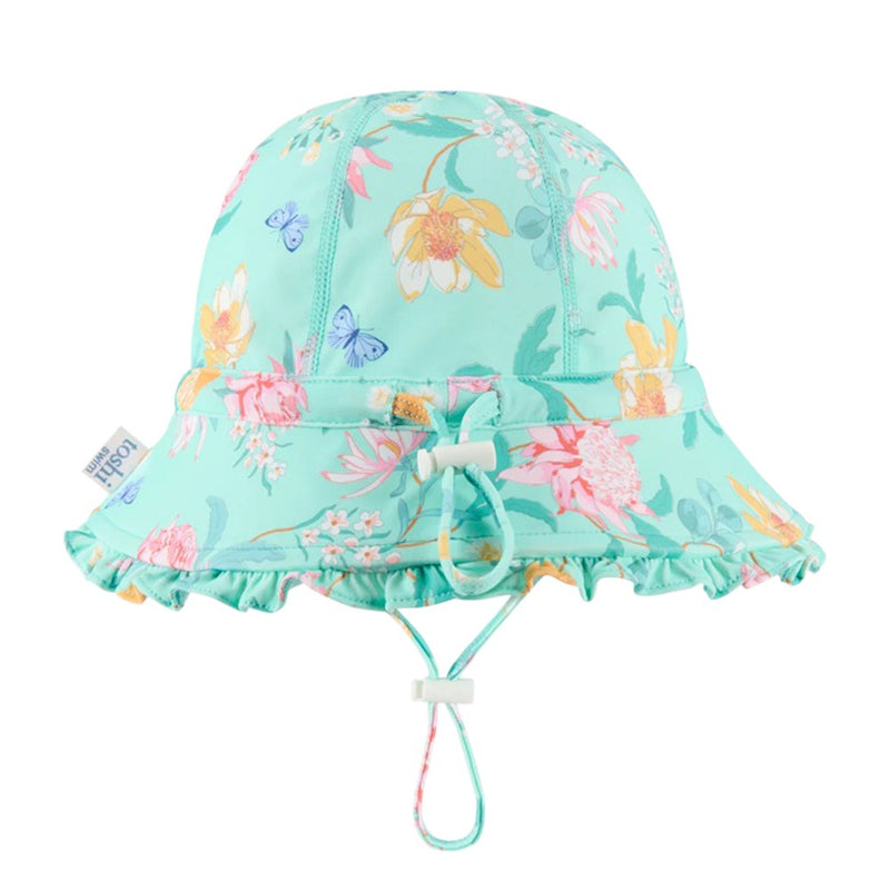 The Toshi Swim Bell Hat Ripple Waratah Mint is a light turquoise baby sunhat with a floral and butterfly print, ruffled brim, adjustable chin strap, UPF50+ protection, and a small cloth side tag.