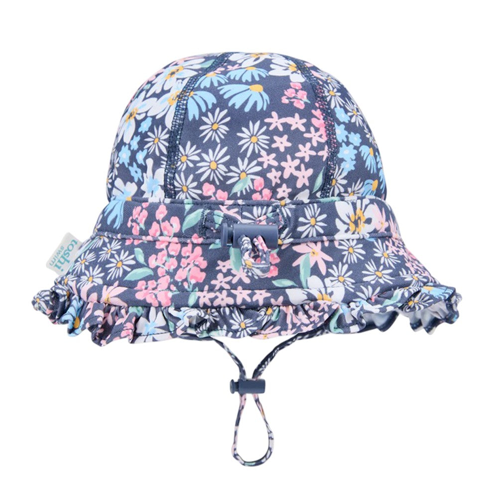The Toshi Swim Bell Hat Ripple Wattle Dusk is a navy blue baby sunhat with a pink, yellow, and white floral print, ruffled brim, UPF50+ protection, adjustable chin strap, and a front bow detail.