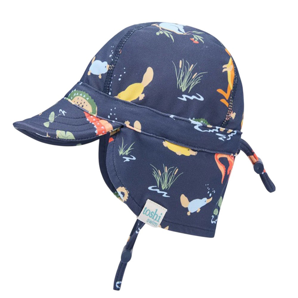 The Toshi Swim Flap Cap Paradise Kakadu Moonlight by Toshi is a navy blue kids’ cap with UPF50+ sun protection, bright animal and plant prints, curved brim, chin strap, drawstring, and neck flap—ideal for baby swimwear.