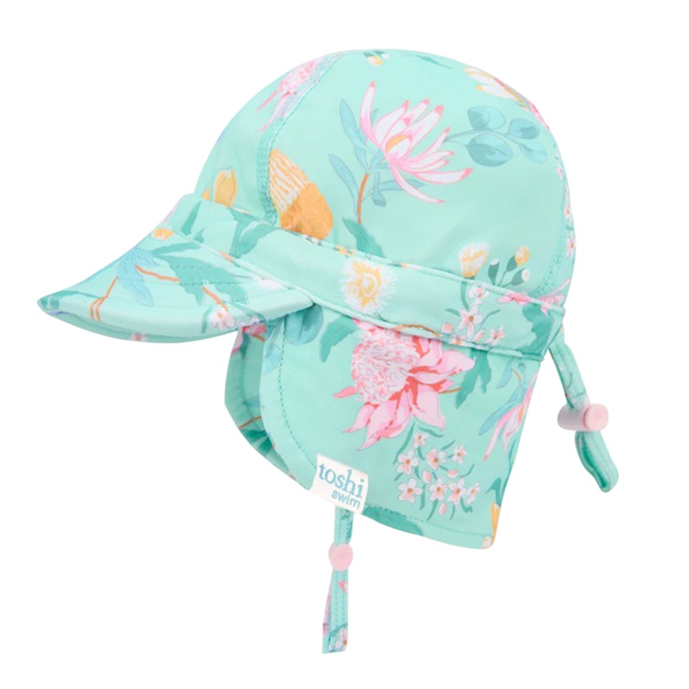 The Toshi Swim Flap Cap Paradise Waratah Mint is a baby swimwear essential featuring a light blue floral pattern, UPF50+ sun protection, front brim, neck flap, adjustable chin strap, back toggle, and a small "toshi swim" label.