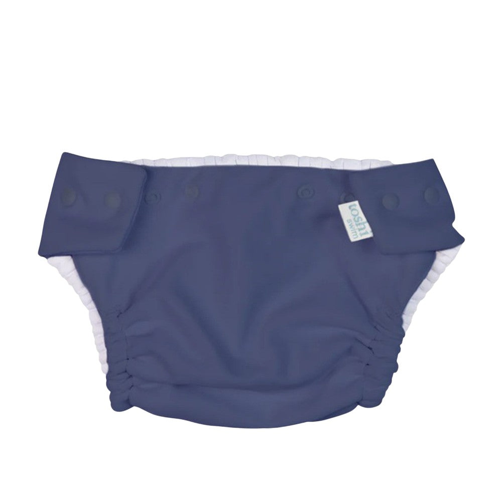 The Toshi Swim Nappy Beachcomber Moonlight by Toshi is a reusable dark blue swim nappy with side snap buttons and a white inner lining, shown flat on a white background.