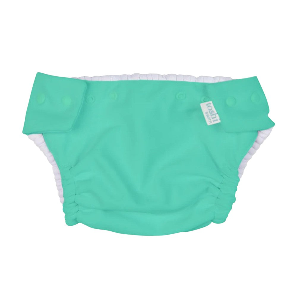 The Toshi Swim Nappy Beachcomber Seagrass is a reusable turquoise swim nappy with white lining and adjustable side snaps, shown on a plain white background—stylish, sustainable swimwear by Toshi for babies.