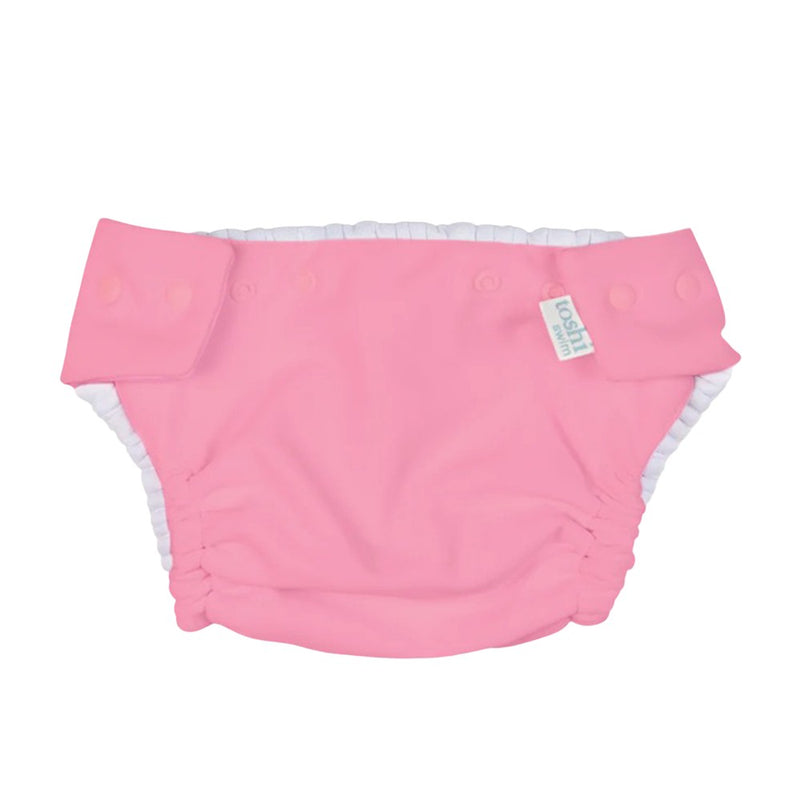 The Toshi Swim Nappy Beachcomber Watermelon is a pink reusable swim nappy with white elastic leg openings, snap side buttons, and a fabric waistband tag—ideal for stylish and practical baby swimwear.