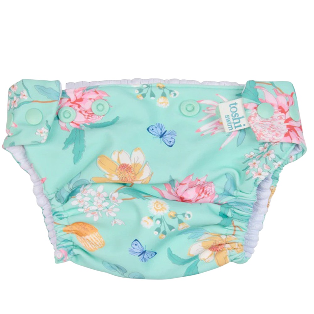The Toshi Swim Nappy Paradise Waratah Mint by Toshi is a reusable baby swim nappy with a mint background, vibrant floral prints, adjustable side snaps, and elastic leg openings.