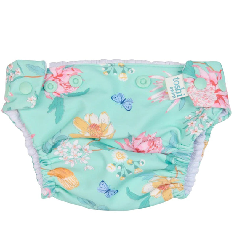 The Toshi Swim Nappy Paradise Waratah Mint by Toshi is a reusable baby swim nappy with a mint background, vibrant floral prints, adjustable side snaps, and elastic leg openings.