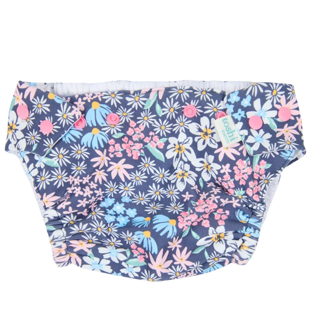 The Toshi Swim Nappy Paradise Wattle Dusk features a reusable design with a vibrant floral print on a dark blue background, making it the perfect stylish swimwear choice for your baby.