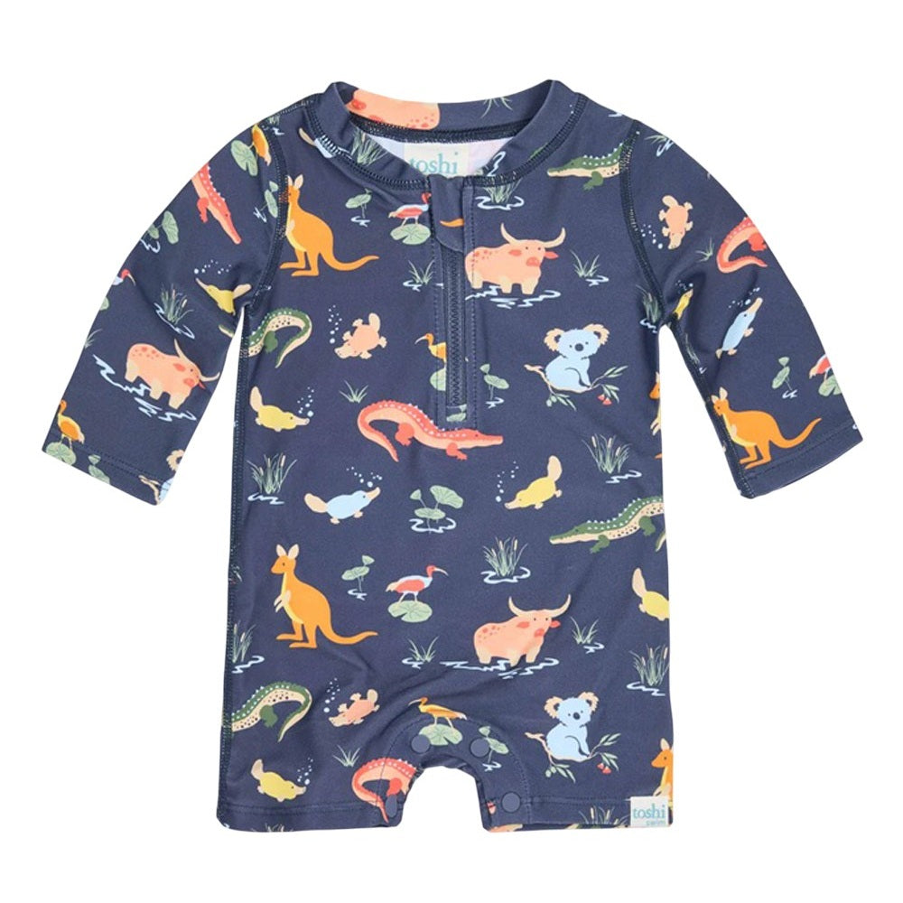 The Toshi Swim Onesie L/S Splash Kakadu Moonlight features a navy blue base with vibrant Australian animal patterns, long sleeves, front zipper, and UPF 50+ sun protection—perfect swimwear for your baby’s outdoor adventures.