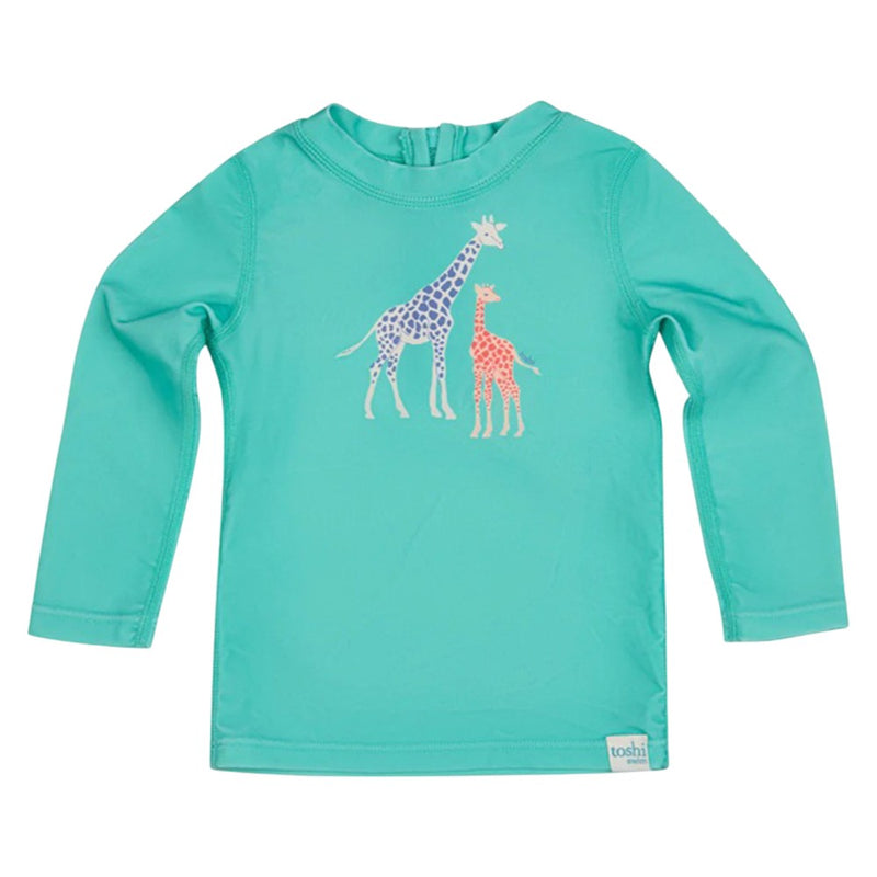 The Toshi Swim Rashie L/S Splash Congo Seagrass by Toshi is a turquoise long-sleeve rashie for kids, featuring two spotted giraffes—one purple, one orange—in the center. It offers UPF50+ sun protection, perfect for outdoor swim fun.