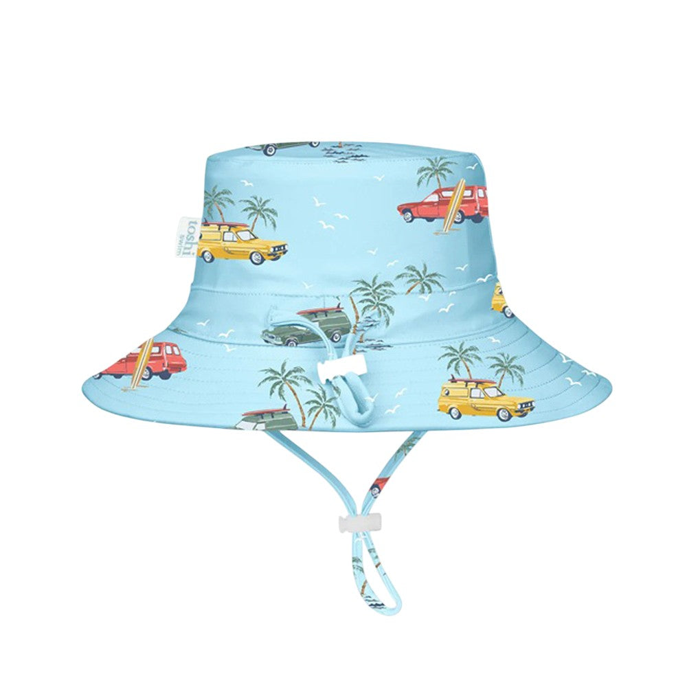 The Toshi Swim Sunhat Paradise Swell Seekers Sky features palm trees, seagulls, and vintage cars on light blue fabric, offers UPF50+ protection, an adjustable chin strap, and pairs perfectly with baby swimwear.