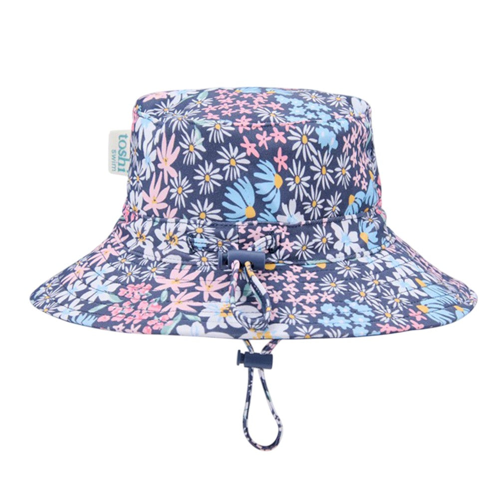 The Toshi Swim Sunhat Paradise Wattle Dusk by Toshi features a blue, pink, and white floral print, adjustable chin strap, UPF50+ sun protection, and a side tag—ideal for stylish baby swimwear.