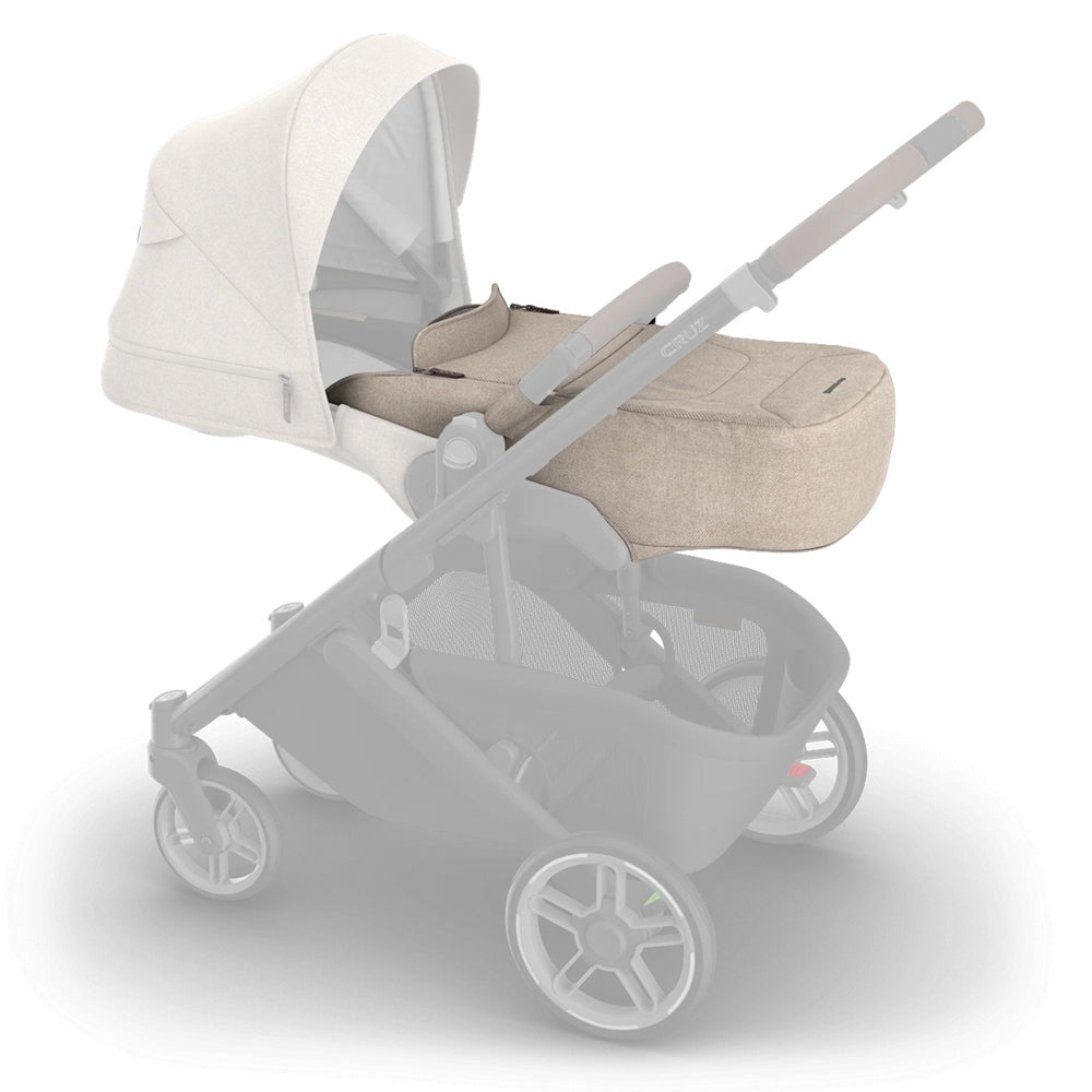 The UPPAbaby CRUZ V3 Infant Cover, shown in beige with a matching bassinet and canopy, attaches to the stroller for all-weather protection—an ideal accessory from UPPAbaby.