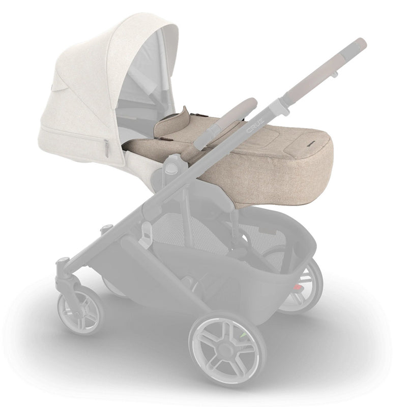 The UPPAbaby CRUZ V3 Infant Cover, shown in beige with a matching bassinet and canopy, attaches to the stroller for all-weather protection—an ideal accessory from UPPAbaby.