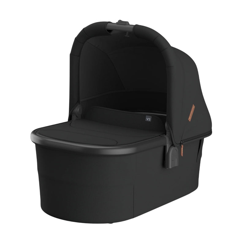 The UPPAbaby V3 Bassinet by UPPAbaby is a black bassinet with a rounded hood, soft fabric sides, flat base, breathable mattress, top handle, zippered side section, and is suitable for overnight sleep.