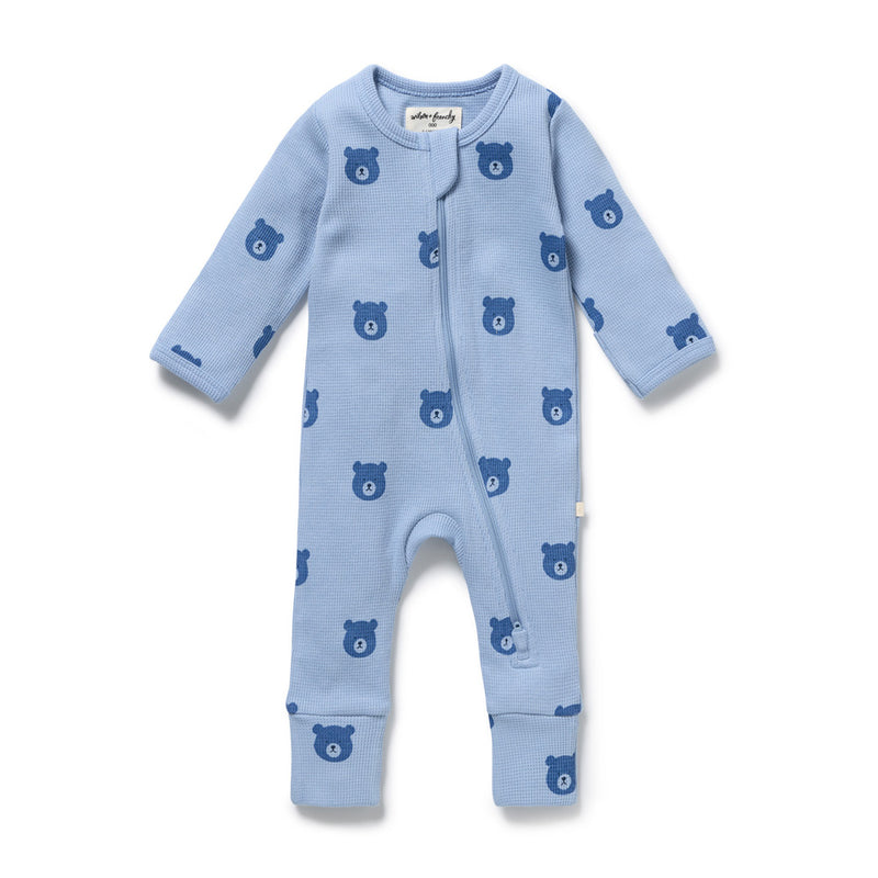 The Wilson & Frenchy Bear Hugs Organic Waffle Zipsuit is a light blue, GOTS-certified baby sleepsuit with long sleeves and legs, darker blue bear face pattern, and a diagonal front zipper from collar to left leg.