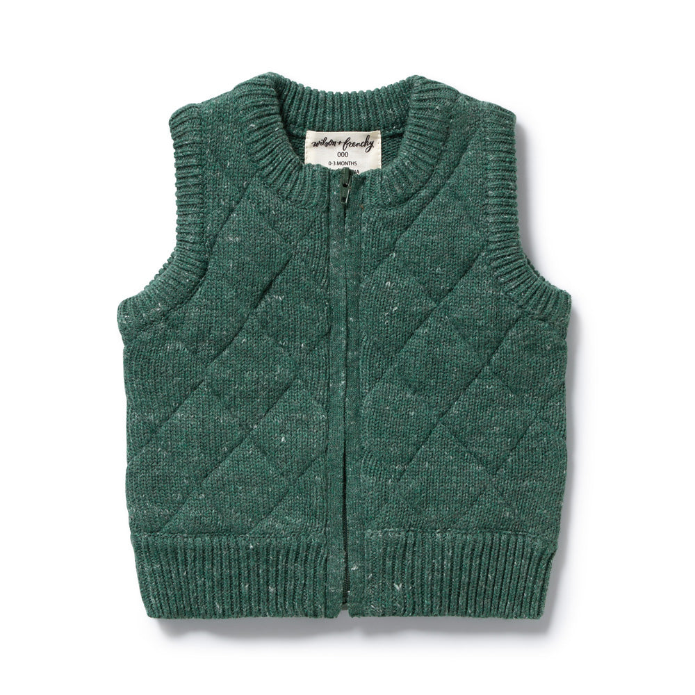 The Wilson & Frenchy Clover Organic Knitted Vest is a green, sleeveless baby vest made from organic cotton, featuring a quilted diamond pattern, ribbed edges, front zipper, and neckline fabric tag—perfect for cozy layering.