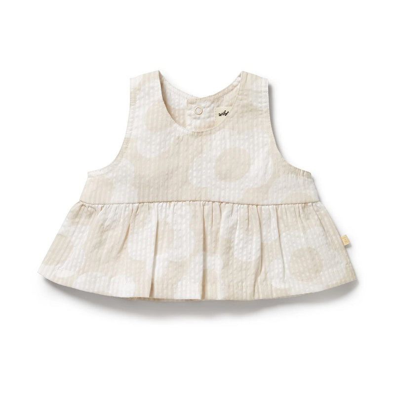 The Wilson & Frenchy Daisy Bloom Organic Top is a beige sleeveless cotton seersucker piece with a round neckline, single button at the collar, circular pattern, and ruffled hem. The lightweight fabric feels soft and comfortable.