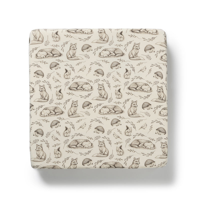 The Wilson & Frenchy Foxglove Forest Organic Sheet is a cream-colored fitted sheet featuring brown-toned sketched foxes, hedgehogs, and plants, shown from above on a white background.