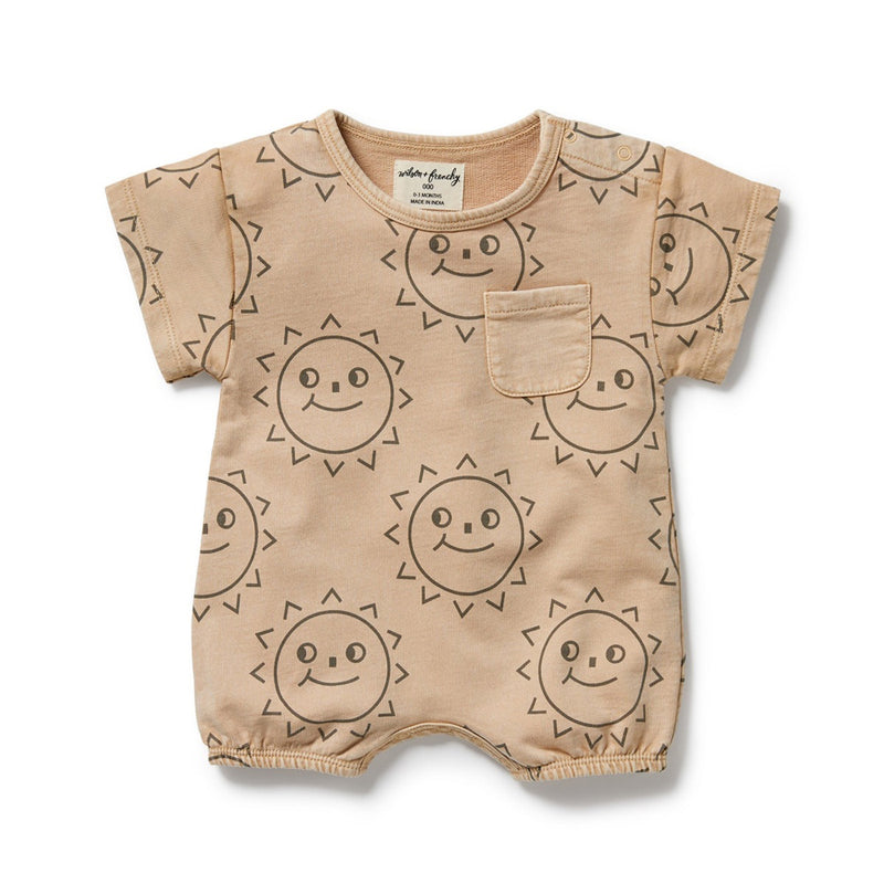 The Wilson & Frenchy Happy Days Organic Sweat Growsuit is a beige, GOTS-certified cotton romper with short sleeves, front pocket, dark brown sun face print, and convenient snap buttons on one shoulder and at the crotch.