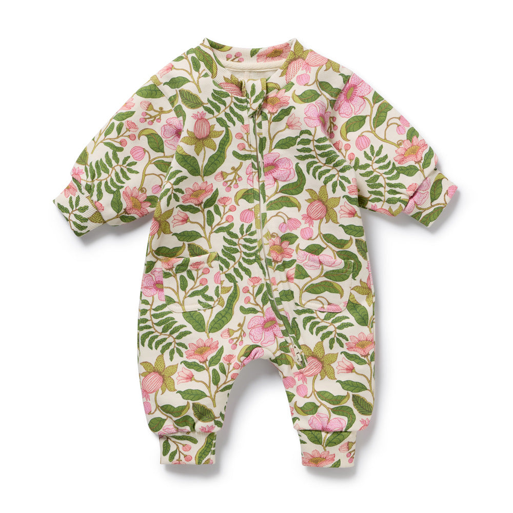 The Wilson & Frenchy Ma Fleur Organic Terry Growsuit features long sleeves and legs, a colorful floral print with green leaves and pink flowers on white, and a front zipper for easy changes.