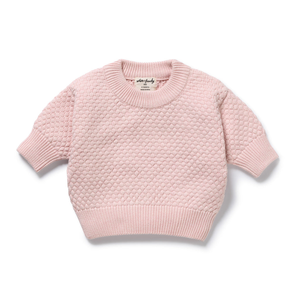 The Wilson & Frenchy Marshmellow Organic Knitted Bubble Jumper is a light pink, short-sleeve baby jumper with a diamond-textured design and ribbed cuffs, collar, and hem, displayed flat on a white background.
