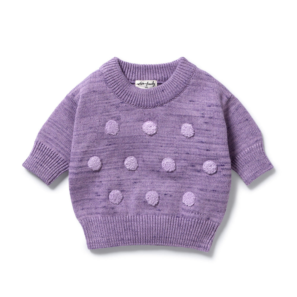 The Wilson & Frenchy Mulberry Organic Knitted Bauble Jumper is crafted from soft organic cotton and features a ribbed collar, cuffs, and hem with rows of raised pom-poms on the front.