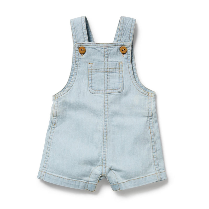 The Wilson & Frenchy Organic Denim Overall is a light blue kid's piece made from organic cotton, with adjustable shoulder straps, wooden buttons, chest pocket, and short legs. The overall is shown laid flat on a white background.