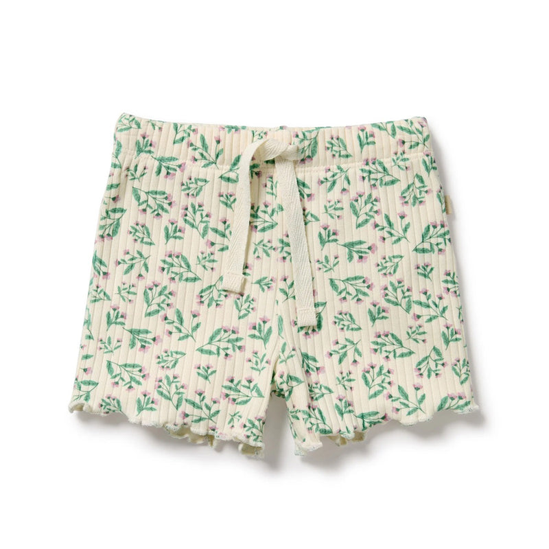 The Wilson & Frenchy Periwinkle Organic Short features a ribbed knit in cream, with a green leafy and pink floral pattern, wavy hem, and drawstring waist. Made from GOTS-certified organic cotton. Displayed on a plain white background.
