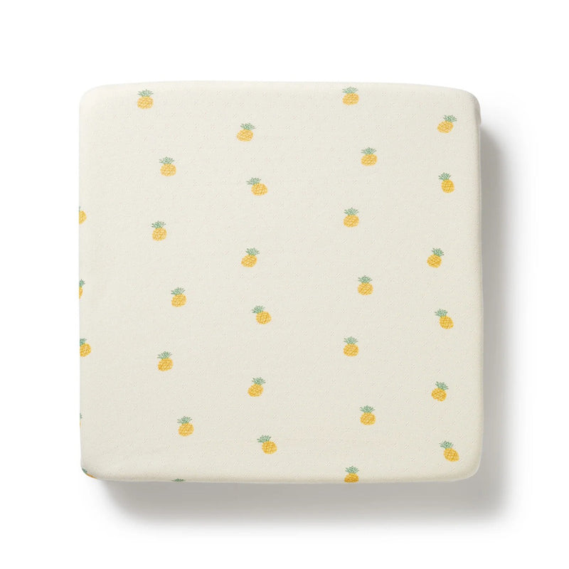 The Wilson & Frenchy Piney Pals Organic Pointelle Cot Sheet by Wilson & Frenchy is GOTS-certified and features a cream base with small, evenly spaced yellow pineapples with green tops on white.