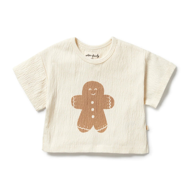 The Wilson & Frenchy Spice & Nice Organic Crinkle Tee is a cream-colored, crinkle cotton top for toddlers with a smiling gingerbread print, textured fabric, and short sleeves—a perfect casual choice for festive Christmas fun.