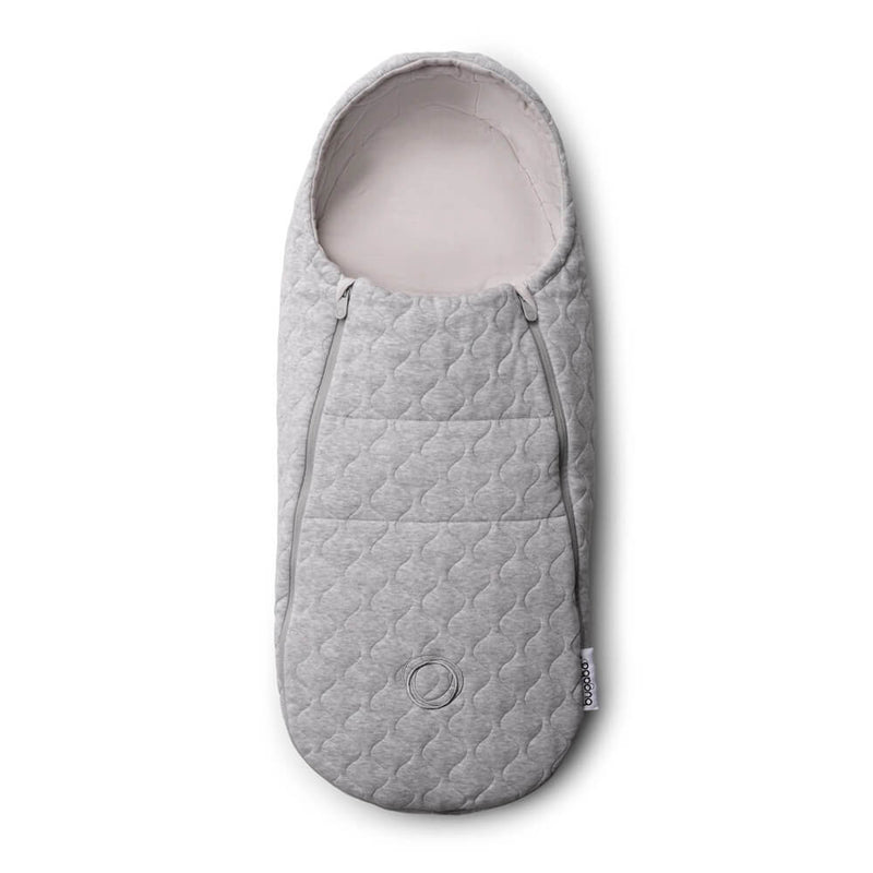 The Bugaboo Newborn Inlay is a gray, quilted sleeping bag with soft fabric and a rounded bottom. Seen from above, it’s a cozy pram accessory with a logo patch—perfect for keeping your baby warm during strolls.
