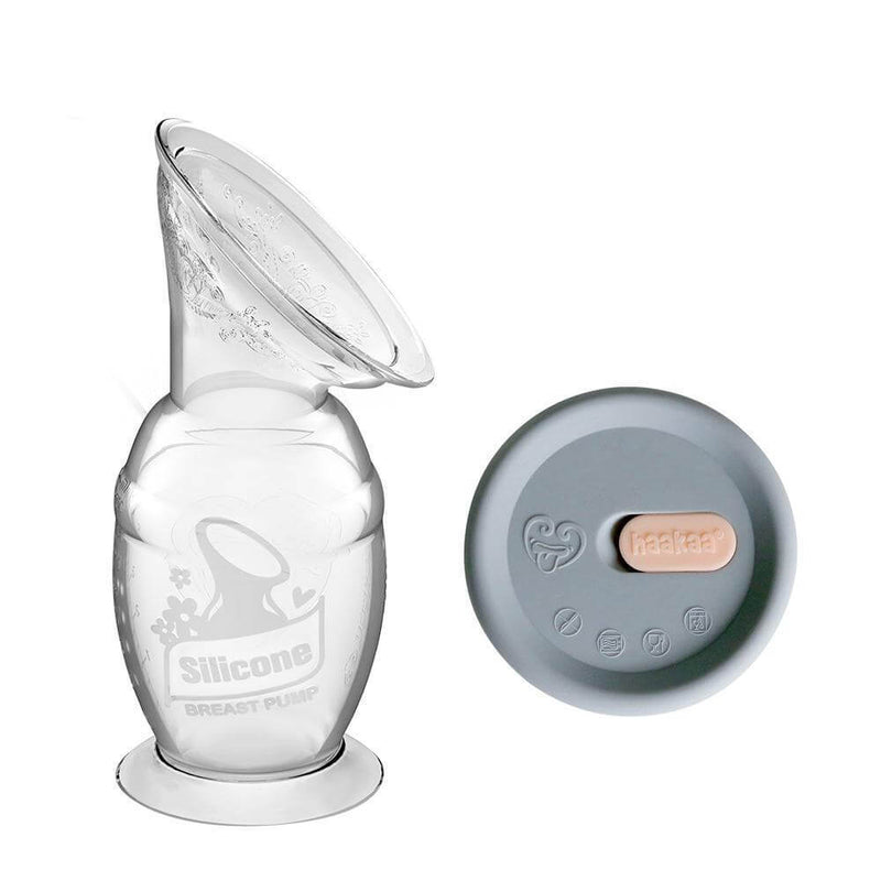 The Haakaa 150ml Silicone Breast Pump with Suction Base & Silicone Cap Gift Box is shown on a white background, featuring the clear pump with floral pattern and wide mouth beside a round gray silicone cap with a beige tab.