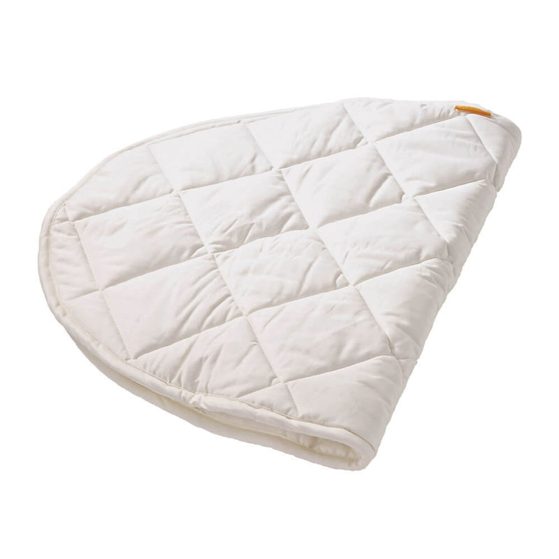 A folded, quilted white pad with a diamond pattern and rounded end rests on a white background—the Leander Junior Bed Organic Mattress Protector by Leander, featuring a soft quilted top mattress design.