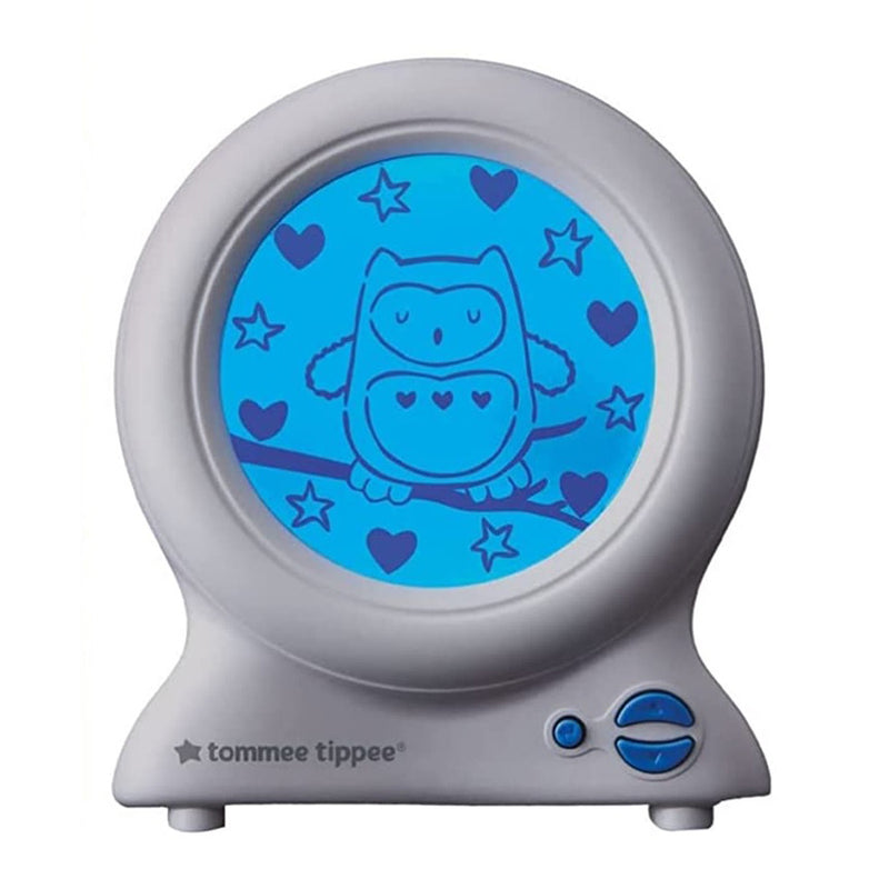 The Tommee Tippee Groclock USB by Gro Company is a nightlight and sleep trainer with a round blue screen showing an owl with heart details on a branch, surrounded by stars and hearts. The gray base has a control dial.