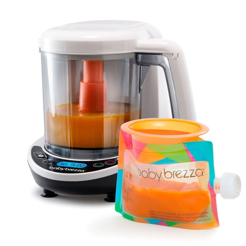 A Baby Brezza One Step Food Deluxe Maker with orange puree sits beside a colorful "babybrezza" reusable pouch, also filled with orange baby food and sealed with a white cap.