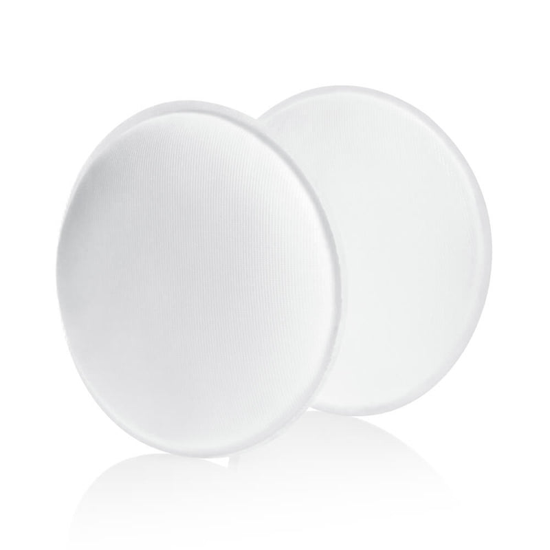 Two round, white Medela Washable Bra Pad 4pk pads are stacked with a slight overlap on a white background, highlighting their soft texture and gentle shadow.