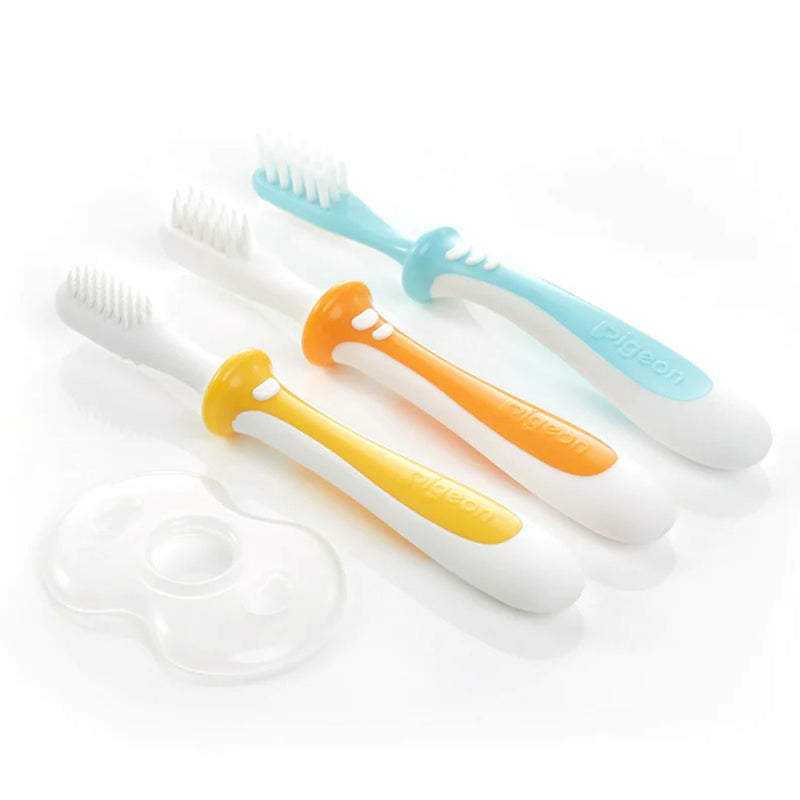 The Pigeon Training Toothbrush Set by Pigeon includes three baby toothbrushes with white handles and blue, orange, and yellow accents, plus a clear oval protective cover—ideal for teething babies—all displayed on a white surface.