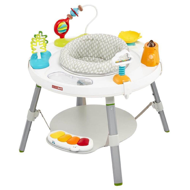 The Skip Hop Explore & More 3-Stage Activity Centre by Skip Hop features a 360-degree rotating seat, colorful edge toys, a four-key piano, and a lower circular shelf on sturdy gray and white legs.